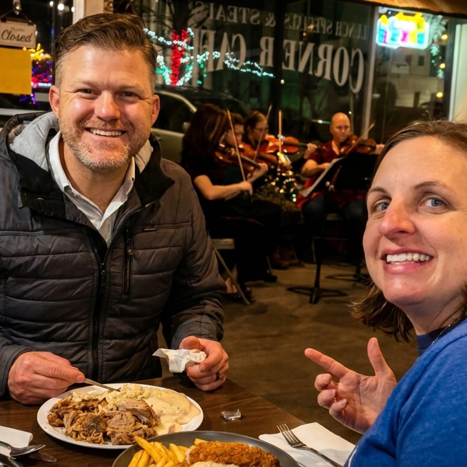 Smiling couple enjoying a meal at a restaurant with live violin music in the background.