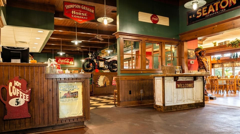 Rustic restaurant interior with wooden counters, vintage signs, a motorcycle display, and dining area.